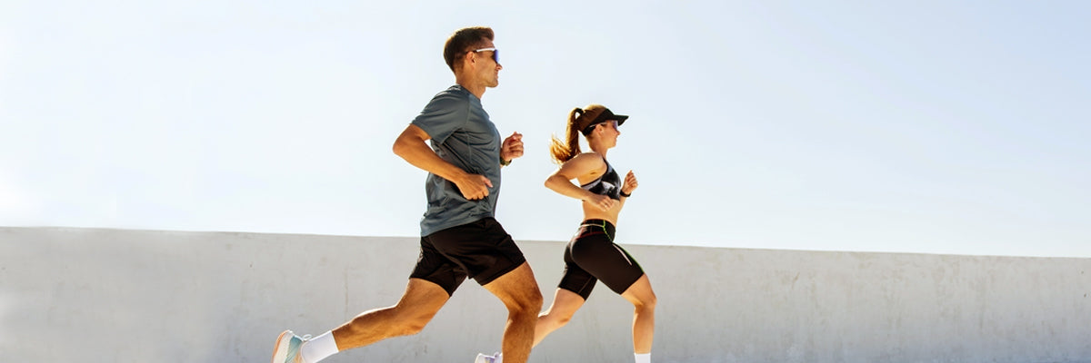 Man and woman jogging outdoors in athletic wear under clear sky